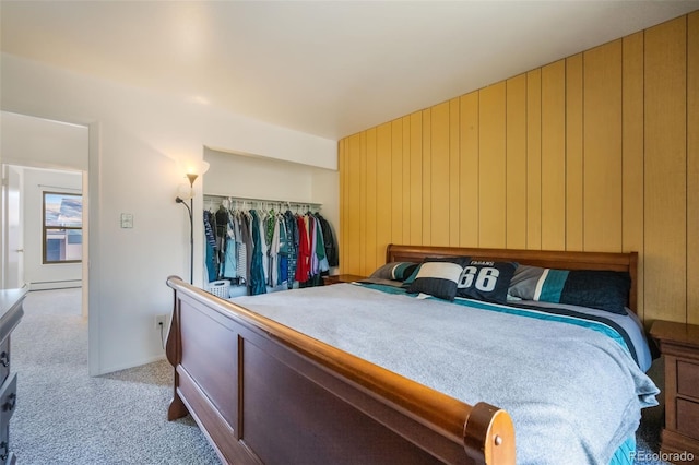 bedroom featuring wood walls, a closet, light colored carpet, and a baseboard radiator