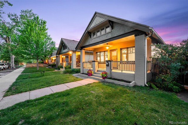 view of front of home featuring covered porch, a yard, and brick siding