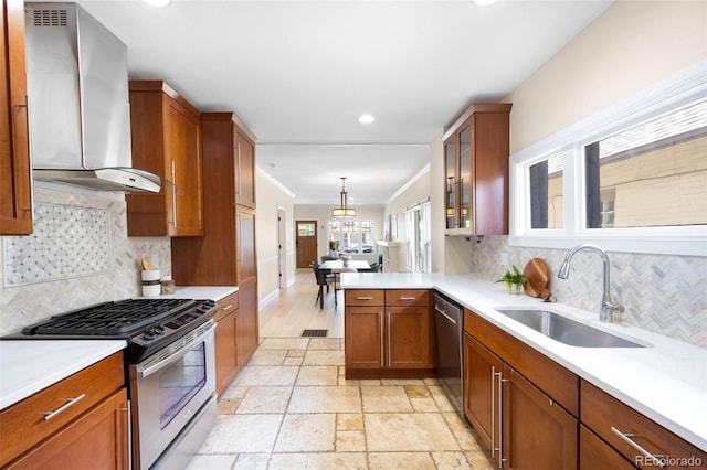 kitchen featuring appliances with stainless steel finishes, wall chimney exhaust hood, a sink, light countertops, and recessed lighting