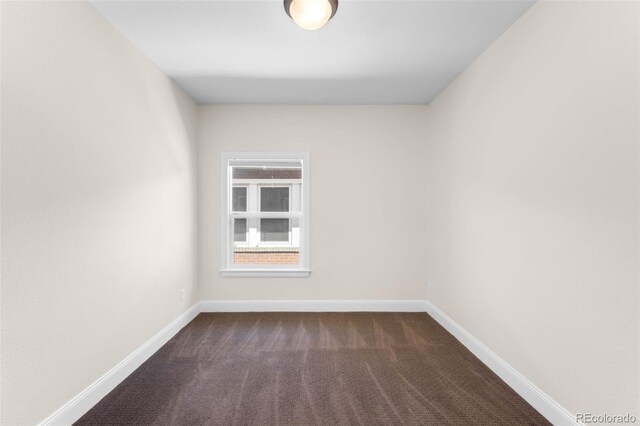 unfurnished room with dark carpet and baseboards
