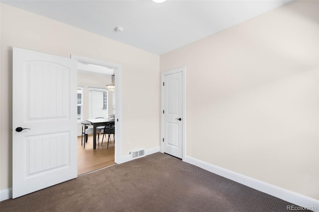 unfurnished bedroom featuring dark carpet and baseboards