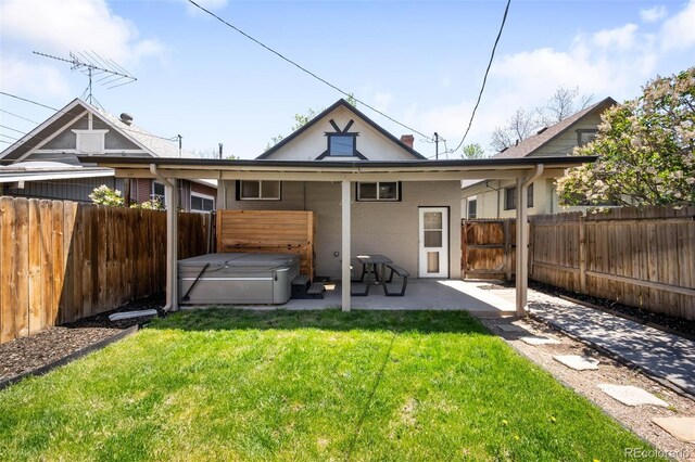 rear view of property with a hot tub, a patio area, and brick siding