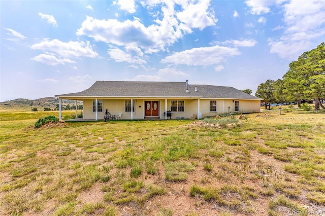 rear view of property with covered porch and a yard