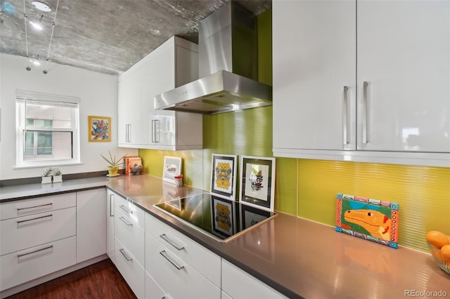 kitchen with black electric stovetop, wall chimney range hood, white cabinetry, and dark hardwood / wood-style floors