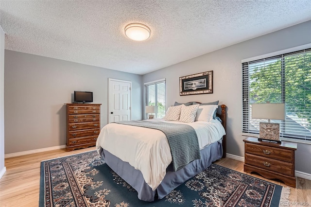 3752 S Helena Way, Aurora, CO 80013 - bedroom featuring a textured ceiling, multiple windows, light wood finished floors, and a closet