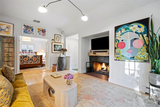 living room featuring baseboard heating, vaulted ceiling, and hardwood / wood-style flooring