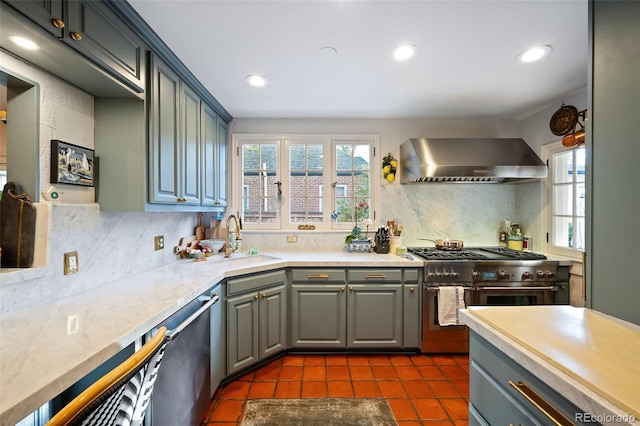 kitchen featuring appliances with stainless steel finishes, dark tile patterned floors, wall chimney exhaust hood, tasteful backsplash, and gray cabinets