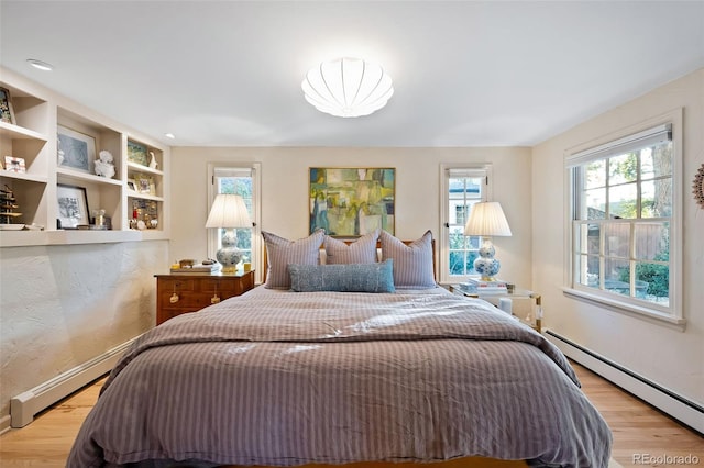 bedroom with light hardwood / wood-style floors and a baseboard radiator