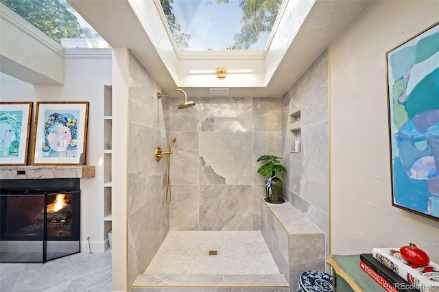 bathroom with built in shelves, a skylight, and a tile shower