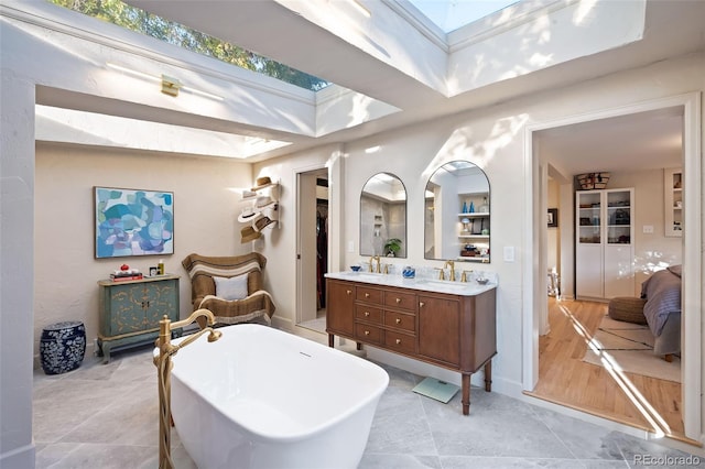 bathroom featuring a tub, vanity, a skylight, and tile patterned flooring