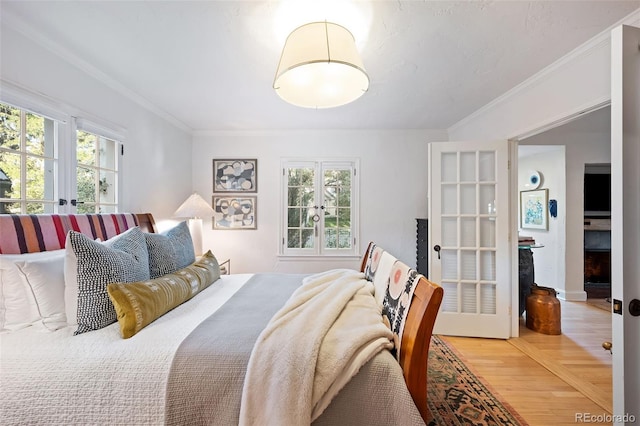 bedroom with wood-type flooring, crown molding, and french doors