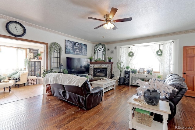 living area featuring a textured ceiling, ornamental molding, dark wood-style flooring, and a ceiling fan