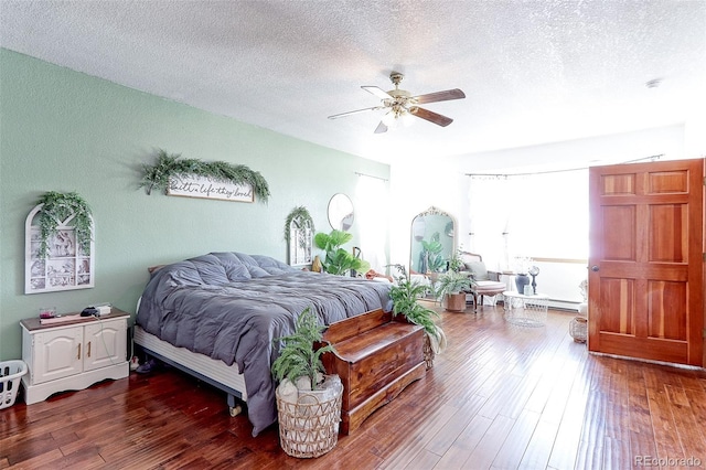 bedroom with dark wood-style floors, ceiling fan, a textured ceiling, and baseboard heating