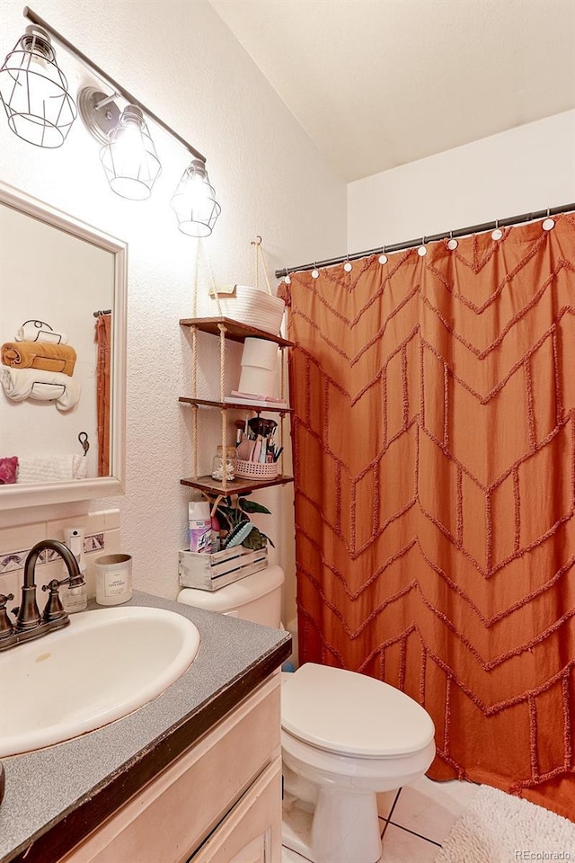 full bath featuring tile patterned flooring, a textured wall, vanity, and toilet