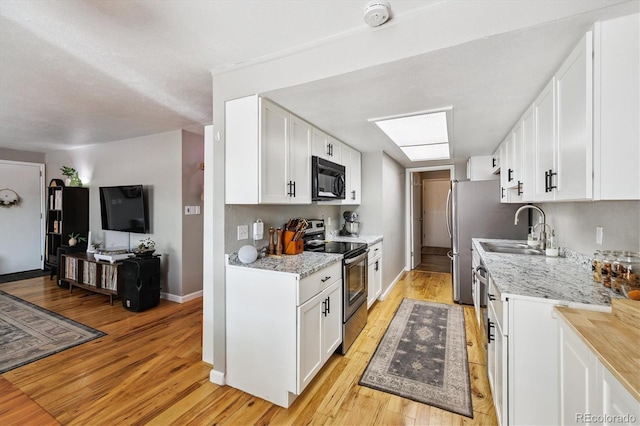 7905 Lowell Blvd Unit B, Westminster, CO 80030 - kitchen featuring stainless steel range with electric stovetop, black microwave, light wood-type flooring, and white cabinets