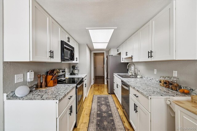 7905 Lowell Blvd Unit B, Westminster, CO 80030 - kitchen with stainless steel appliances, light wood finished floors, white cabinetry, and light stone countertops