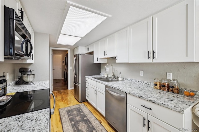 7905 Lowell Blvd Unit B, Westminster, CO 80030 - kitchen with stainless steel appliances, light wood finished floors, white cabinetry, and light stone countertops