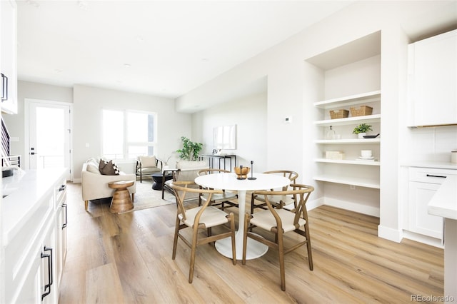 dining space featuring baseboards and light wood-style floors