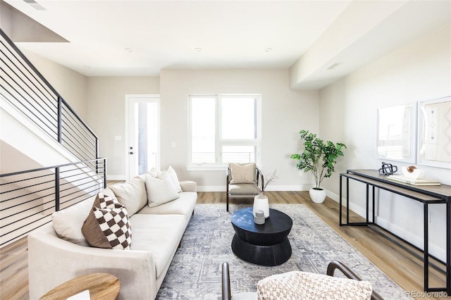 living area with stairway, visible vents, baseboards, and wood finished floors