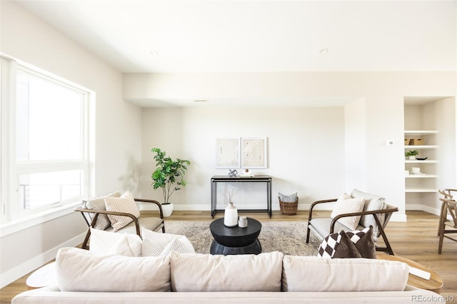 living room with a wealth of natural light, light wood-type flooring, and baseboards