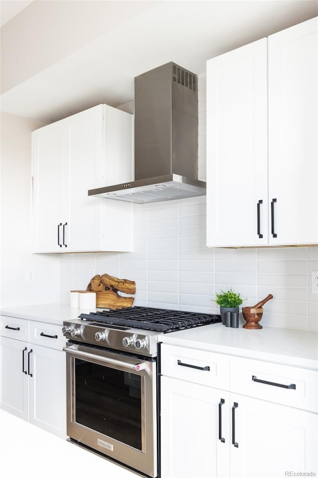 kitchen featuring white cabinetry, light countertops, wall chimney exhaust hood, and stainless steel stove