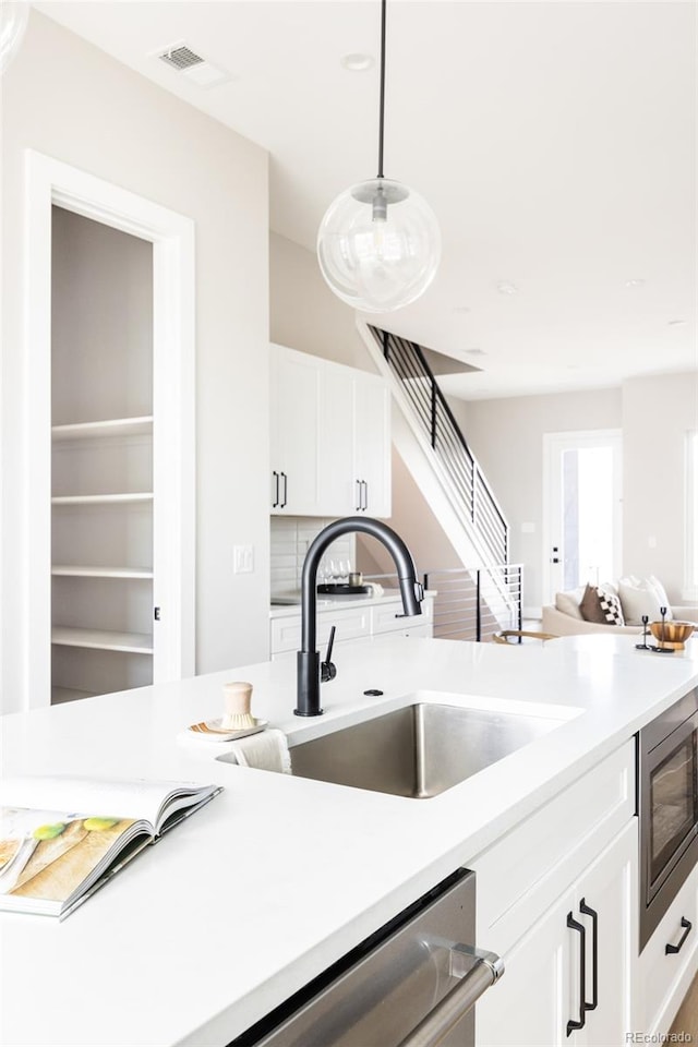 kitchen featuring visible vents, built in microwave, a sink, light countertops, and white cabinets