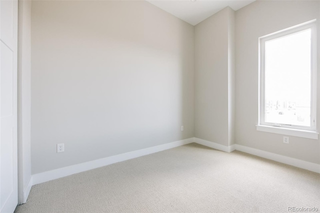 empty room featuring baseboards and light carpet