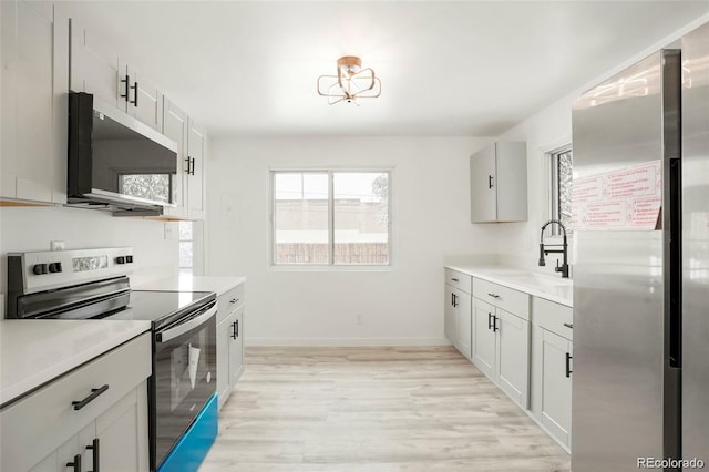 kitchen featuring a sink, light wood-style floors, stainless steel electric stove, and light countertops