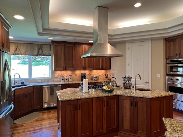 kitchen featuring island exhaust hood, sink, a center island with sink, and stainless steel appliances