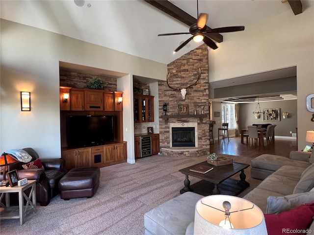 living room featuring a stone fireplace, carpet floors, ceiling fan, wine cooler, and high vaulted ceiling