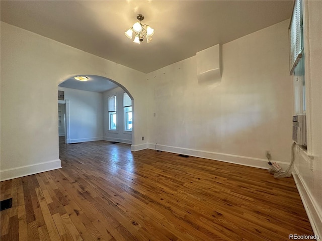 empty room featuring an inviting chandelier and dark hardwood / wood-style floors