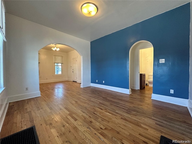 spare room with a notable chandelier and hardwood / wood-style floors