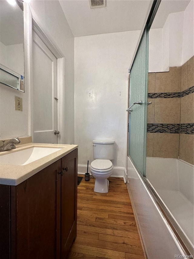 full bathroom with toilet, shower / bath combination with glass door, vanity, and hardwood / wood-style floors