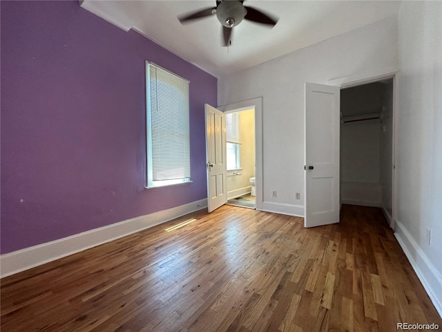 unfurnished bedroom featuring ceiling fan, ensuite bathroom, a closet, and hardwood / wood-style flooring