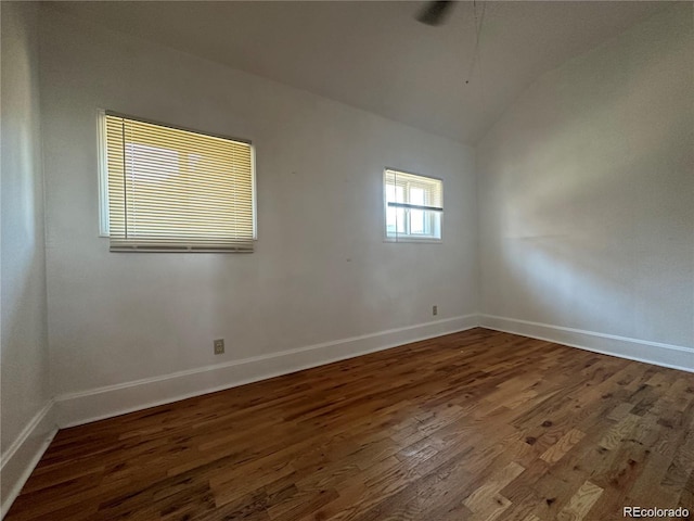 spare room featuring dark hardwood / wood-style flooring and lofted ceiling