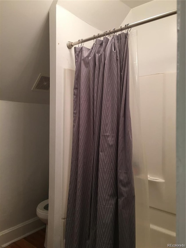 bathroom with toilet, vaulted ceiling, and a shower with shower curtain