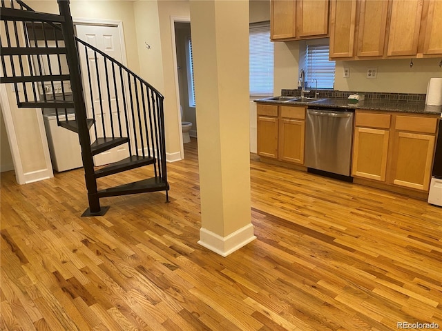 kitchen featuring sink, light wood-type flooring, dishwasher, and dark stone countertops