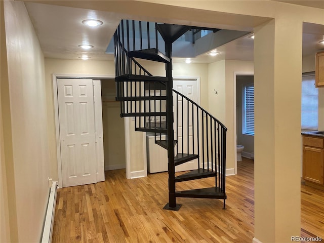 staircase featuring a baseboard heating unit and hardwood / wood-style flooring