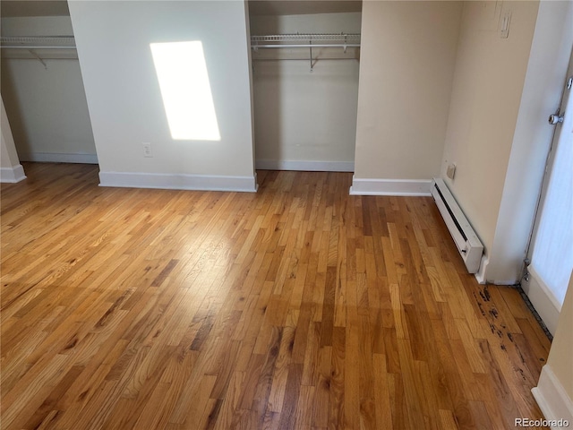 unfurnished bedroom with a baseboard heating unit and light hardwood / wood-style floors