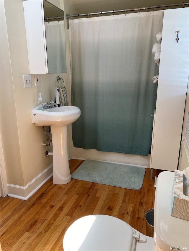 bathroom featuring toilet, wood-type flooring, and walk in shower