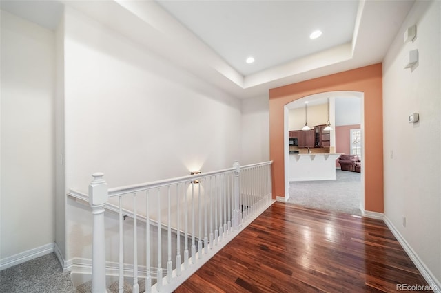 hallway featuring dark wood-type flooring and a tray ceiling