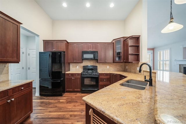 kitchen with black appliances, decorative light fixtures, light stone countertops, sink, and dark wood-type flooring