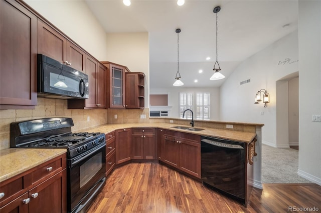 kitchen with sink, black appliances, kitchen peninsula, wood-type flooring, and vaulted ceiling