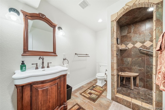 bathroom featuring vanity, toilet, and tiled shower