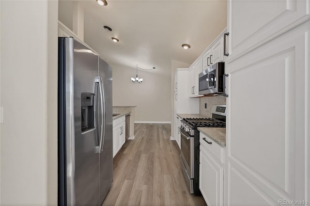 kitchen with light stone counters, white cabinets, decorative light fixtures, appliances with stainless steel finishes, and light hardwood / wood-style floors