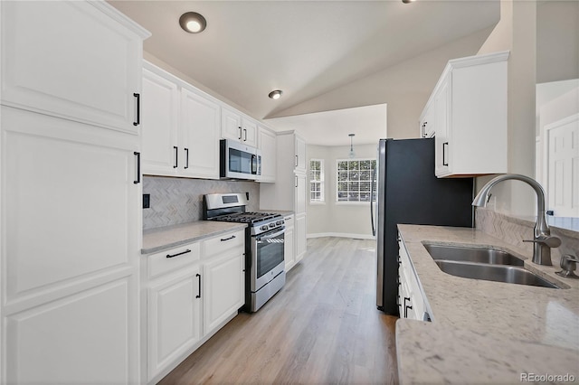 kitchen with white cabinets, appliances with stainless steel finishes, sink, and lofted ceiling