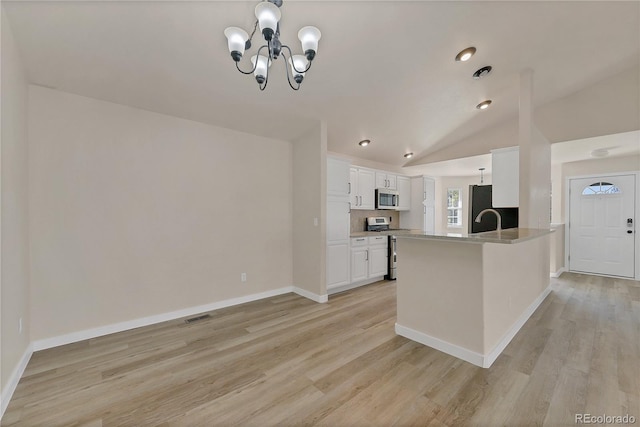 kitchen with white cabinets, lofted ceiling, kitchen peninsula, light hardwood / wood-style flooring, and appliances with stainless steel finishes