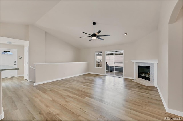 unfurnished living room with a fireplace, lofted ceiling, light wood finished floors, and ceiling fan