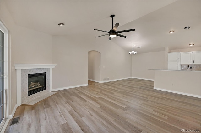 unfurnished living room featuring light wood-style flooring, ceiling fan with notable chandelier, a fireplace, and visible vents