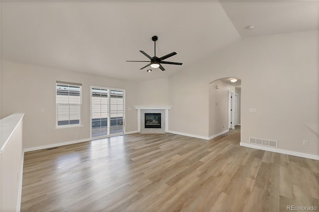 unfurnished living room with visible vents, baseboards, ceiling fan, light wood-style floors, and vaulted ceiling